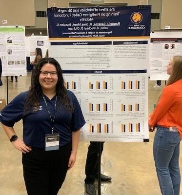 Graduate student stands in front of her poster presentation.